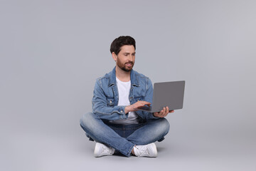 Happy man with laptop on light grey background
