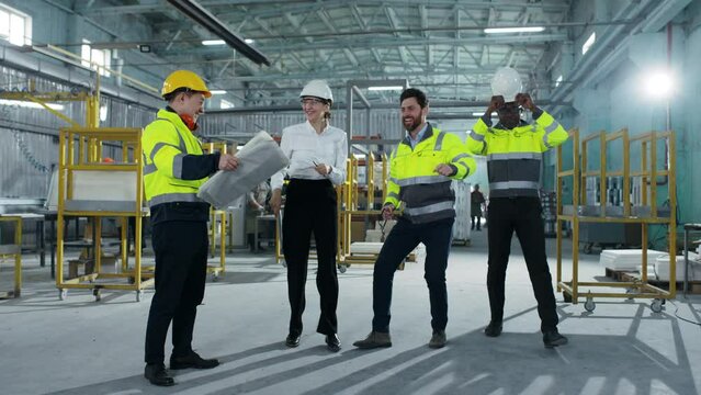 Diversion from work or serious matters on construction site. Managers in yellow vests are dancing and having fun at factory. Multicultural workers enjoy their work. Relaxation at workplace.