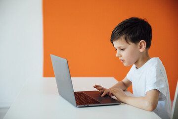 a boy playing on a laptop at a table in the room