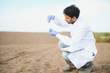 Soil Testing. Indian Agronomy Specialist taking soil sample for fertility analysis. Hands in gloves close up. Environmental protection, organic soil certification, field work, research