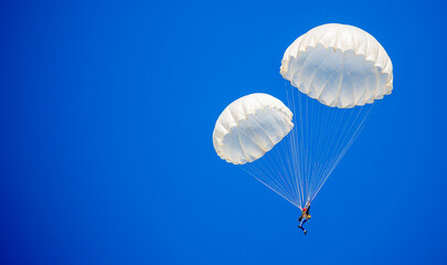 Skydiving. Flying parachutists against the background of the blue sky and mountains. Extreme sport and entertainment.