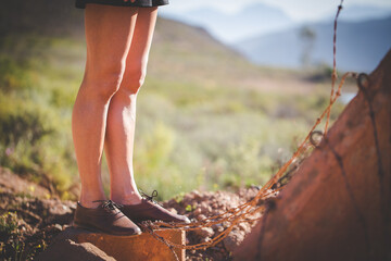 Close up image of a pretty woman with muscular legs walking on a dirt road wearing handmade leather shoes.