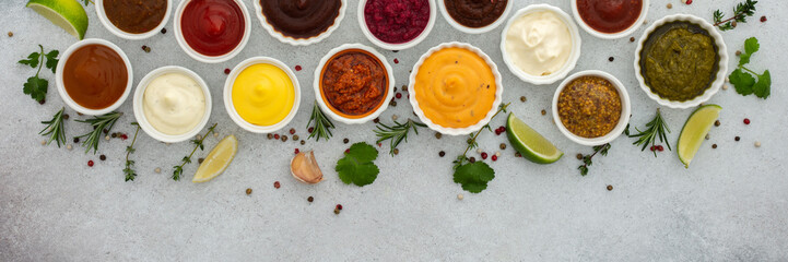 Different types of sauces in bowls with seasonings banner, rosemary and pepper, thyme and garlic, lime and lemon, cilantro, top view, copy space