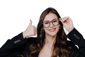 Beautiful brunette young woman with loose wavy hair adjusts spectacles on face toothy smiles looks at camera points up by thumb up gesture at empty space on transparent background. Mockup