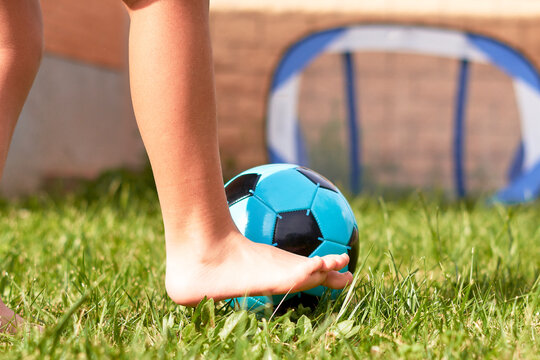 girl plays football barefoot in the garden of her house.