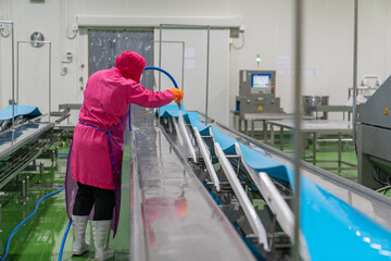 Worker spray water on conveyor after finishing his daily job. - Powered by Adobe