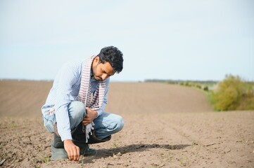 Naklejka na ściany i meble A young Indian farmer inspects his field before sowing.
