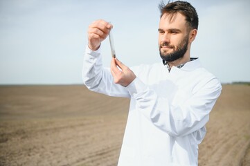 Agronomist studying samples of soil in field