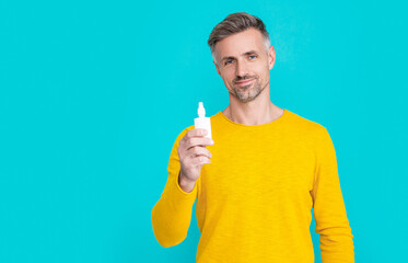 man hold nasal medicine isolated on blue. man hold nasal medicine in studio.