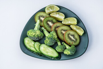 green vegetables - broccoli, kiwi, lime cucumber on a plate