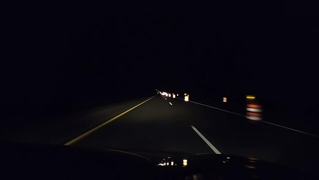 Dash camera view while driving slowly on freeway at night while passing road work signs.