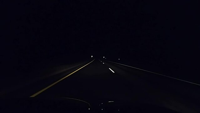 Dash camera view while driving slowly on freeway at night without any street lights.