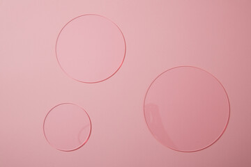 Top view of some round acrylic sheets decorated on pink background. Creative frame with copy space for advertising cosmetic product
