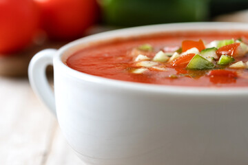 Traditional Spanish gazpacho soup in bowl on wooden table. Close up