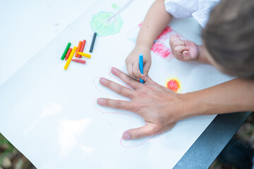 Obraz na płótnie Canvas Family activity drawing son using crayons to draw father's hand