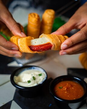 Homemade cheese t&aacute;quenos (deditos) torn in half with different sauces, typical latin dish