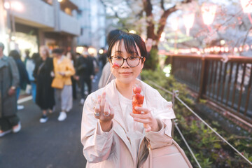 Asian woman eating popular menu in sakura festival Nakameguro Tokyo city at night street travel