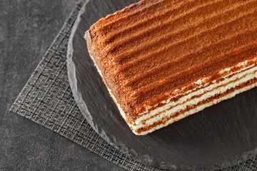 Multi-layered chocolate cake, on slate stone plate round, dark background, side view, selective focus