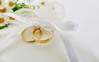 Gold wedding rings on white ring pillow with copy space