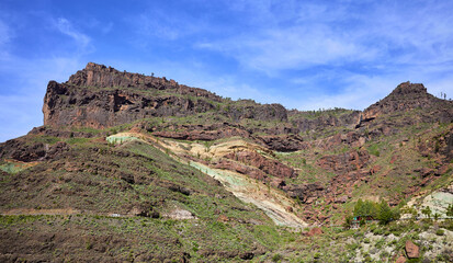 Fototapeta na wymiar Fuente de los Azulejos seen from the road that leads from Mogán to the Aldea de San Nicolás. Emerald green rock formation in the mountains of the Inagua Integral Nature Reserve, in Gran Canaria.