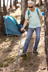Active Senior Man Camping in Mountains. Standing in a front of his Tent. Preparing for going Hiking