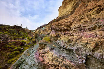 Fuente de los Azulejos de Veneguera, volcanic rocks stratified and colored by the effect of hydromagmatic eruptions. Emerald green, red, yellow rock formation.