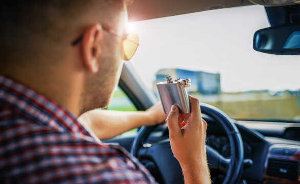 Man drinking alcohol while driving a car. Don't drink and drive