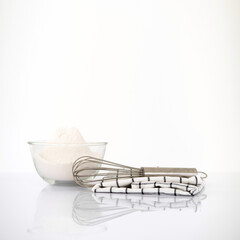 Baking ingredients on white reflect table over defocused white kitchen wall background. front view. Copy Space