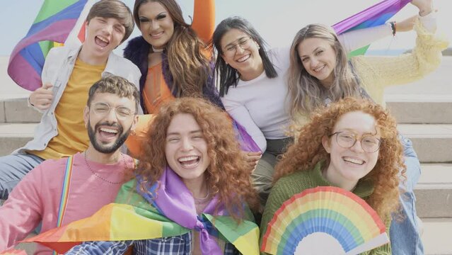 Diverse group of young people celebrating gay pride festival day - Lgbt community concept with guys and girls hugging together outdoors	