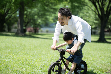 自転車の練習をする親子　新緑の公園でレジャー　ママと男の子　コピースペース左