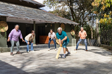 Family members playing cricket in the back yard.