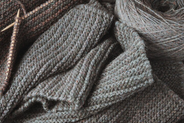 Fototapeta na wymiar Unfinished gray scarf, knitting needles and a round skein of wool.