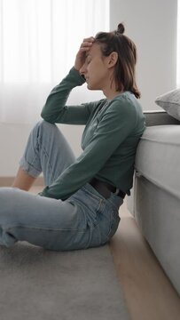 Sad Pensive Hispanic Young Woman Sitting On The Floor In The Living Room