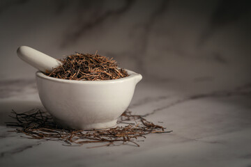 Closeup of Dry Amar Bel (Cuscuta reflexa) roots, in white ceramic mortar and pestle. Front view on...