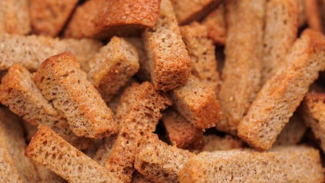 Crispy toasted bread croutons. A pile of hard rusks from dark dry bread close up. Snack for beer. Rye crackers. Snacks rye crackers in a strip. Crouton or brown roasted tostes rotating. 