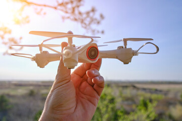 Quadcopter in hand, preparing fly against sky.