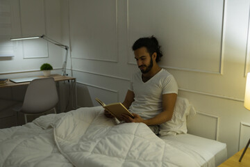 Handsome latin man reading before sleeping