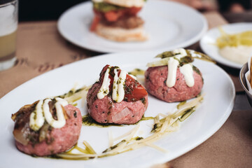 Traditional Chilean meal - crudo - raw meat balls with onions, spices, mayonnaise. tomatoes on a table in a restaurant  