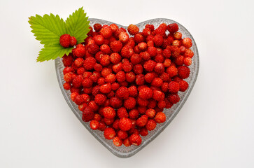 fresh wild strawberries in a heart-shaped bowl flat lay