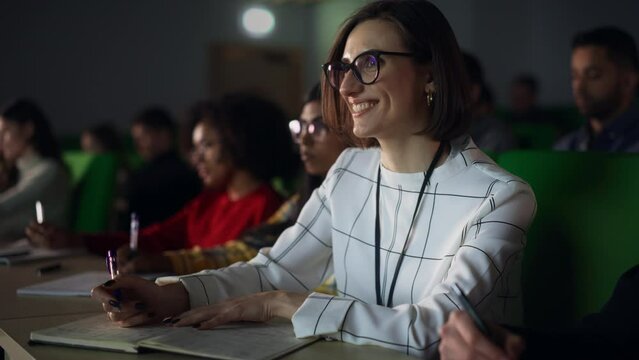 Portrait of a Happy Smart Female Student, Studying in University with Diverse Multicultural Colleagues. She is Writing Down a Summary from the Lecture in Her Notebook
