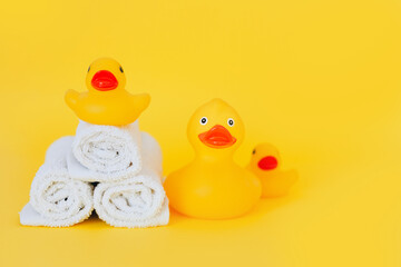 Stacked white towels and bath ducks on yellow background