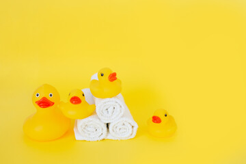 Stacked white towels and bath ducks on yellow background