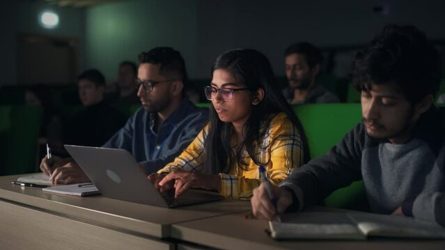Portrait of a Smart Talented Indian Female Student Studying in University with Diverse Multiethnic Classmates. Young Woman Using Laptop Computer and Taking Notes During the Lecture