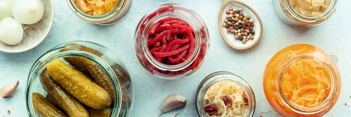 Fermented food panorama, top shot. Homemade vegetable preserves. Sauerkraut, pickles, kimchi etc in...