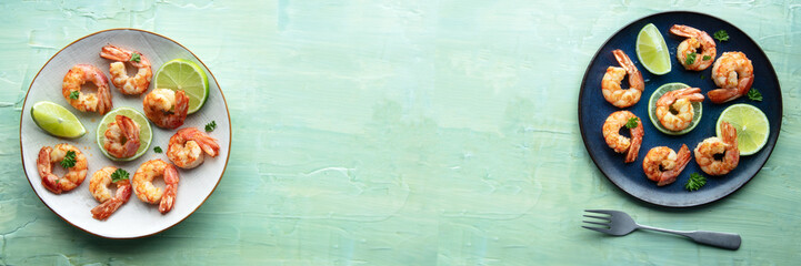 Shrimps, overhead flat lay panorama with copy space. Cooked shrimp with lime, shot from the top on a teal blue background, panoramic banner for a restaurant menu