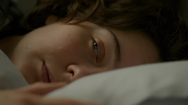 A sleepy girl cannot wake up, she is in a deep depression and does not want to get out of bed. Early in the morning, a female portrait of a sleepy girl who is lying in bed does not want to go to work
