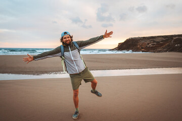 Cheerful man tourist outdoor with backpack walking alone on the beach travel lifestyle active...