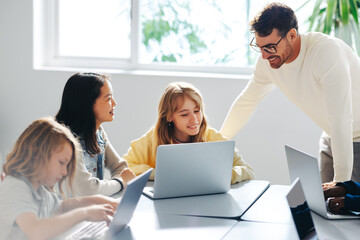 Computer-based learning in an elementary school: Teacher guiding a group of students in a coding...