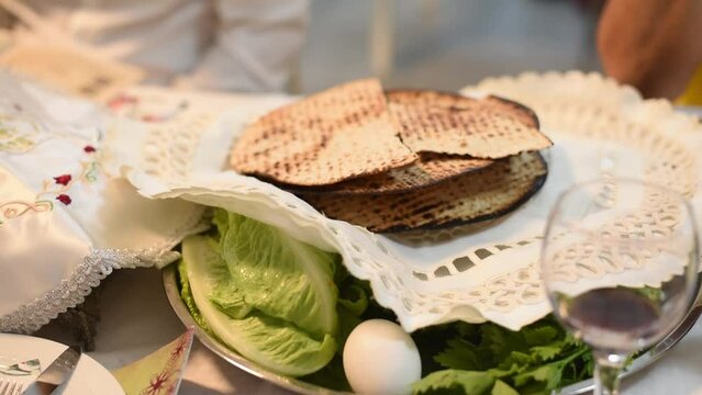 On white traditional table matza prepared for Passover with egg, bottle of wine, glass, green salad and parsley. Spring Holiday of Jewish people. Fasting time