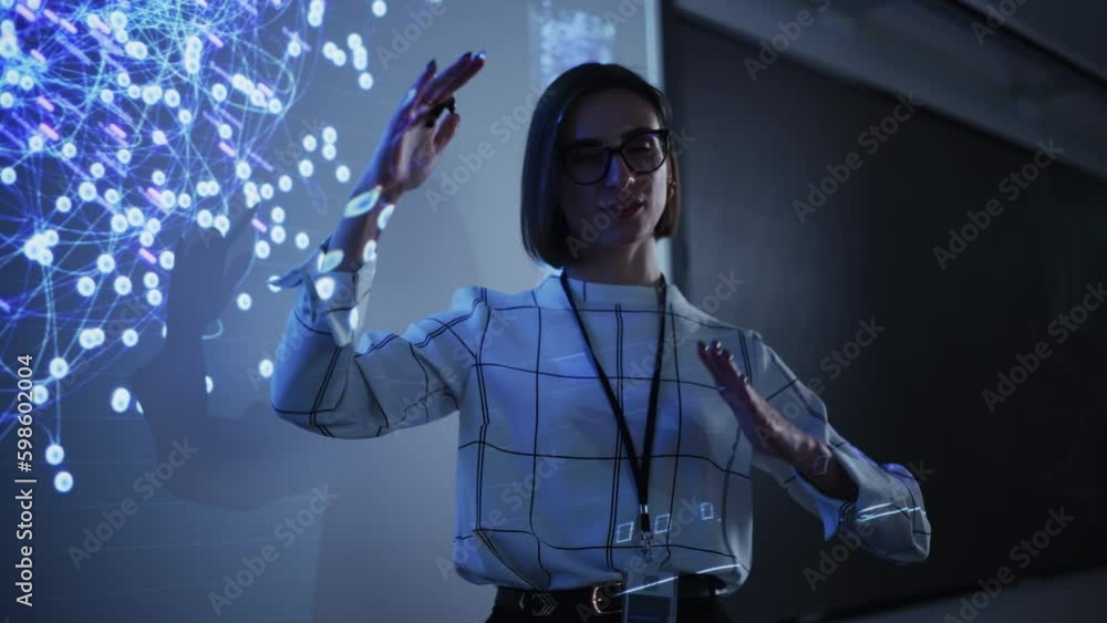 Poster Portrait of a Young Female Professor Explaining Big Data and Artificial Intelligence Research Project in a Dark Room with a Screen Showing a Neural Network Model. Computer Science Education in College